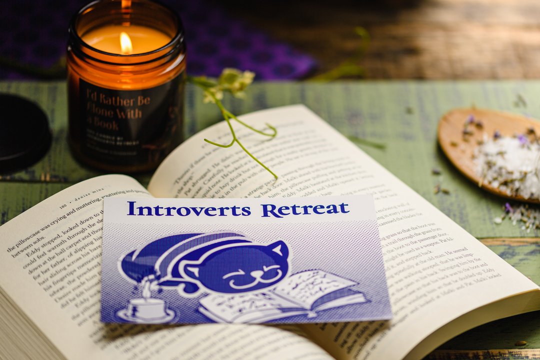 A book with a candle and a card reading Introvert’s Retreat Box